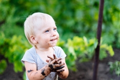 child with blue eyes playing in the mud in the summer on the street